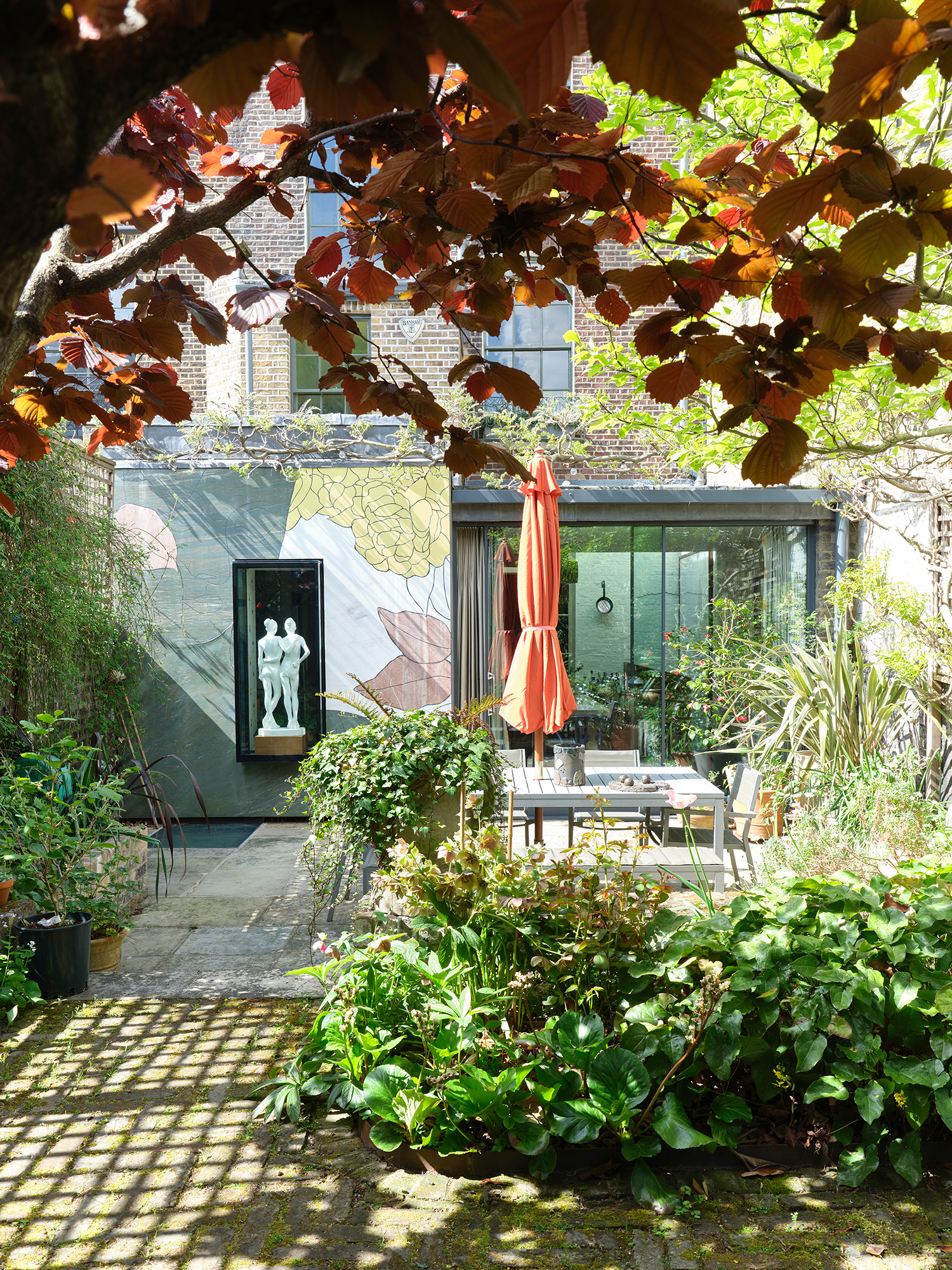 The glass-walled kitchen leads out into the back garden, with artworks and ornamental planting