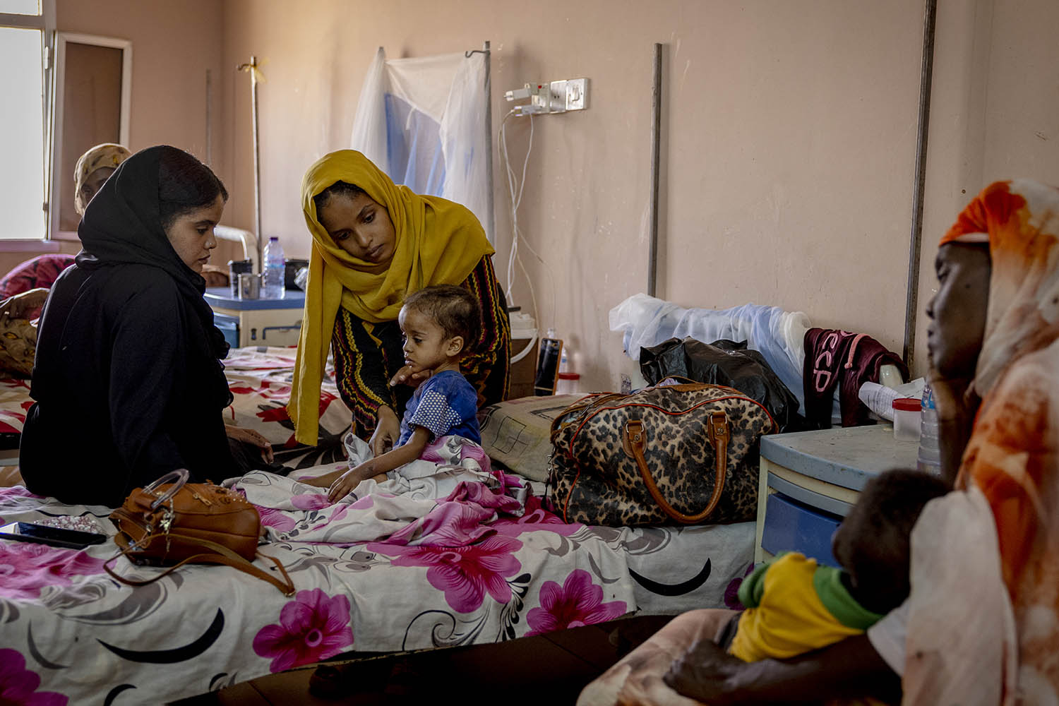 Asmaa Eltayeb, five, who was suffering from malnourishment and tuberculosis, is comforted by her relatives at Al-Buluk paediatric hospital in Omdurman