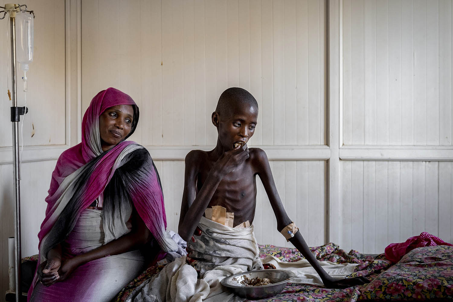 Hassan Adam, 14, has a meal at ﻿Al-Nau hospital alongside his mother, Amona Elhadi. Hassan had only recently started eating again after being shot