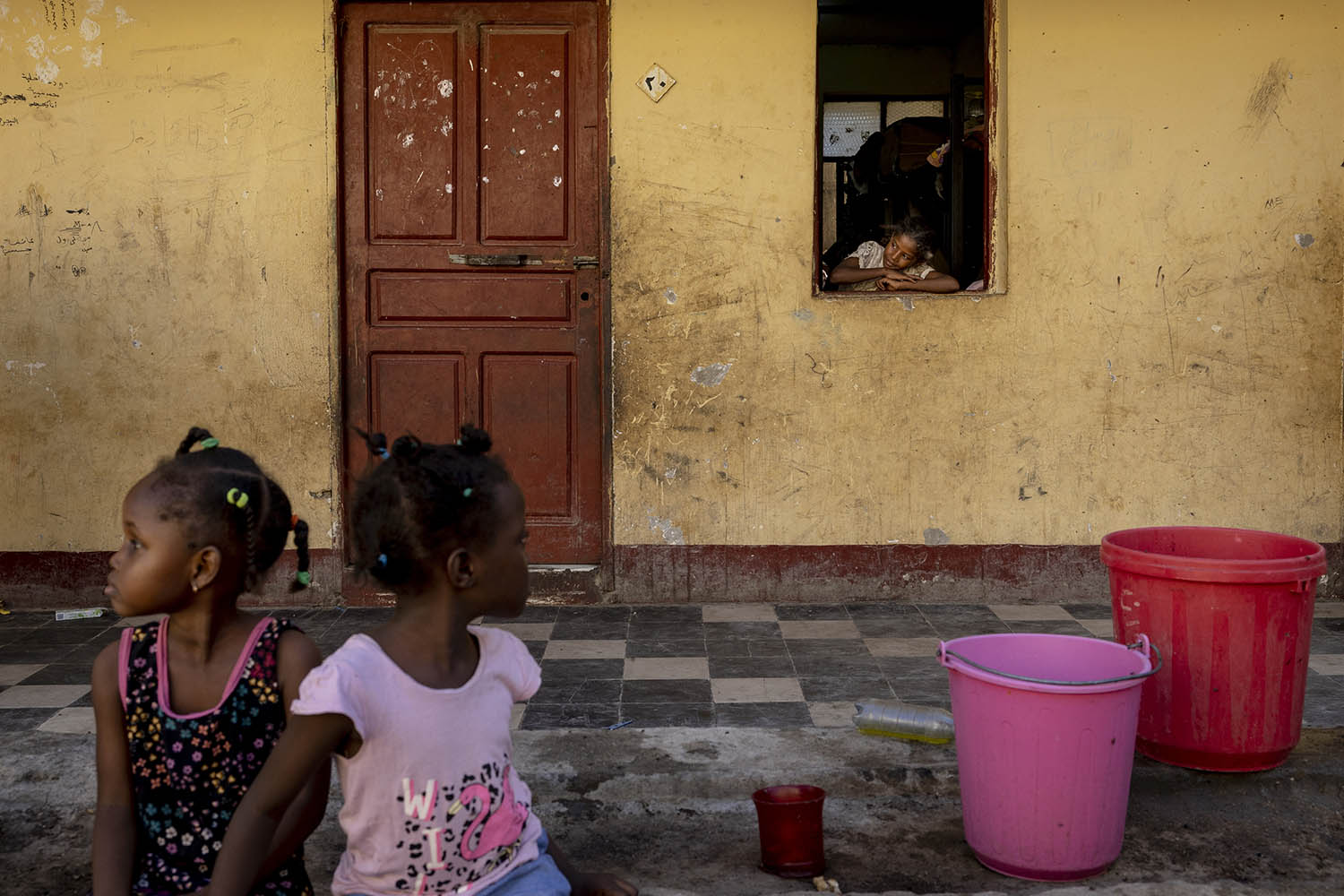 A girl peers from a window in a dormitory in which hundreds of women and children shelter
