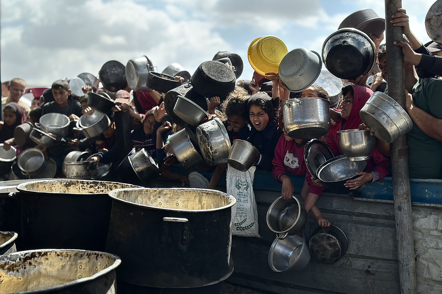 Starving Palestinian children in Khan Younis cluster around trucks distributing food