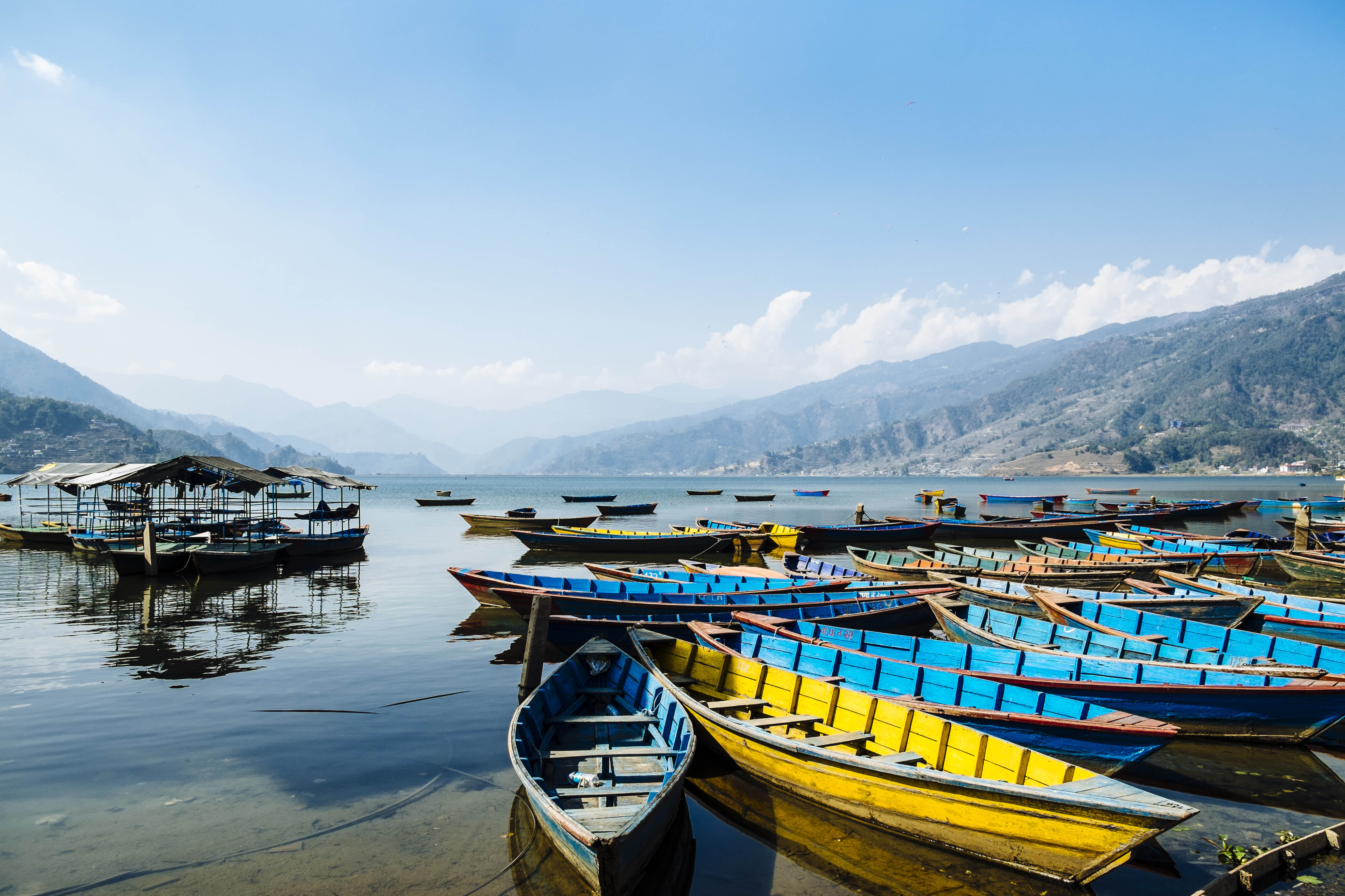 Mirror image: colourful canoes line the shore of Fewa Lake with the foothills of the Himalayas in the distance