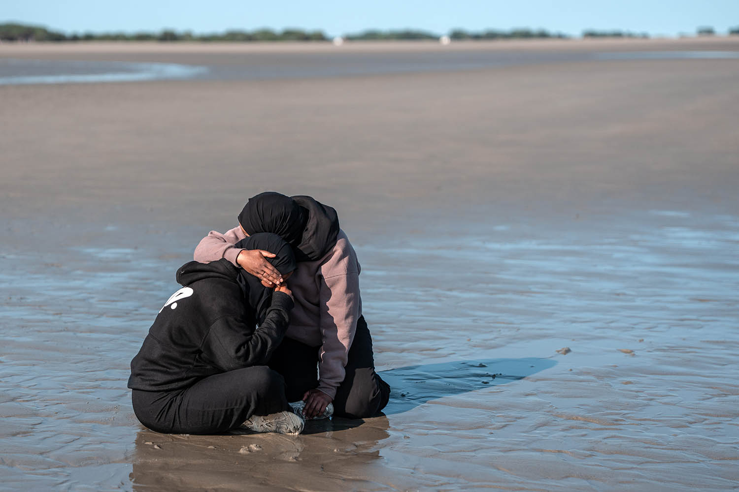 A woman consoles a friend after they missed a dinghy crossing