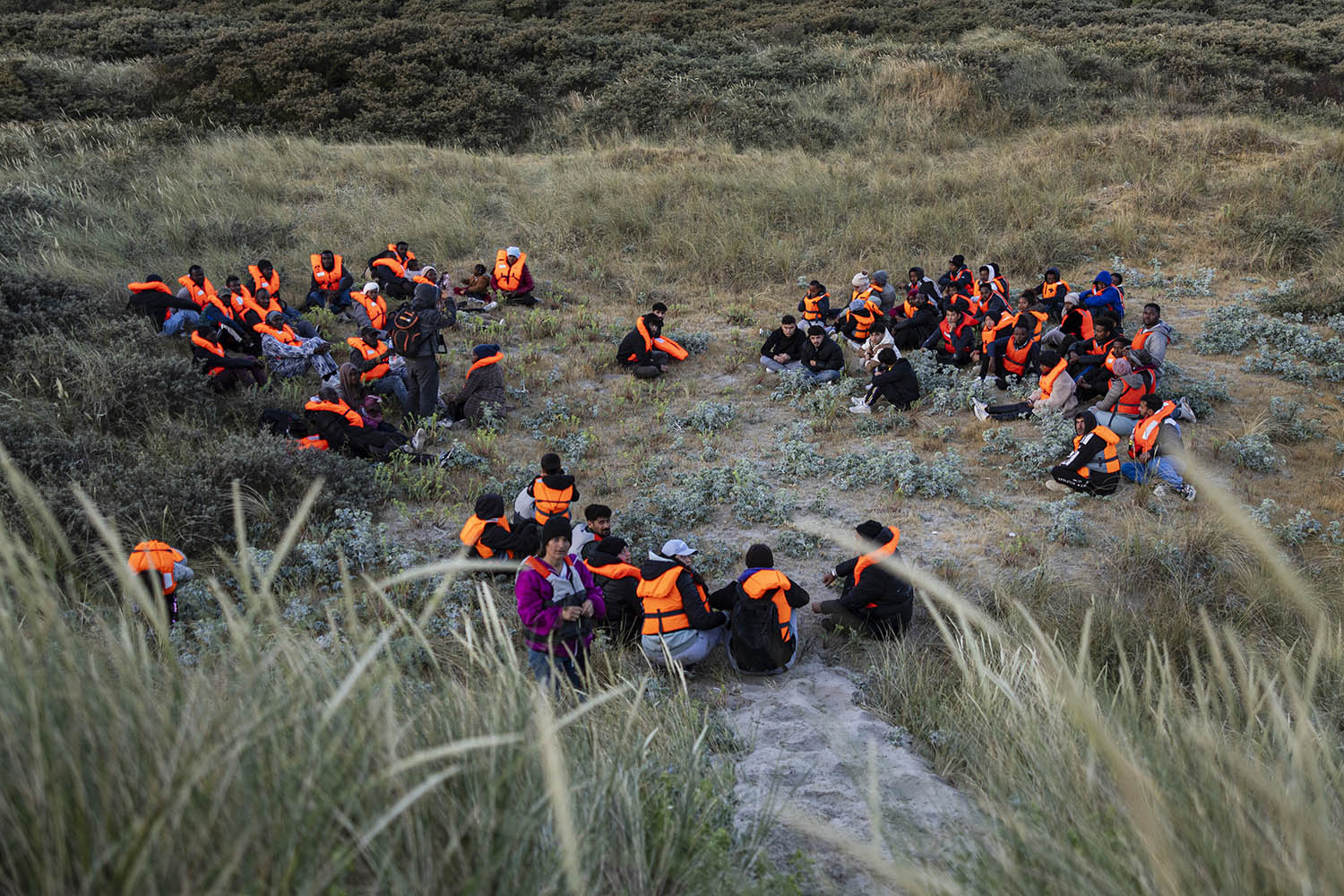 Migrants gather in the dunes at dawn before a dinghy arrives