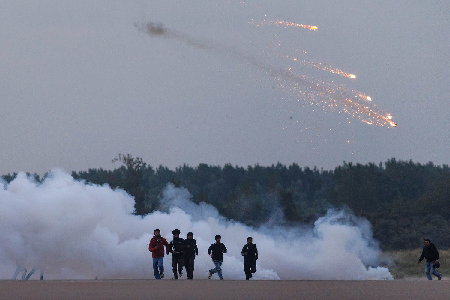 Engulfed by clouds of tear gas, people run from the French police