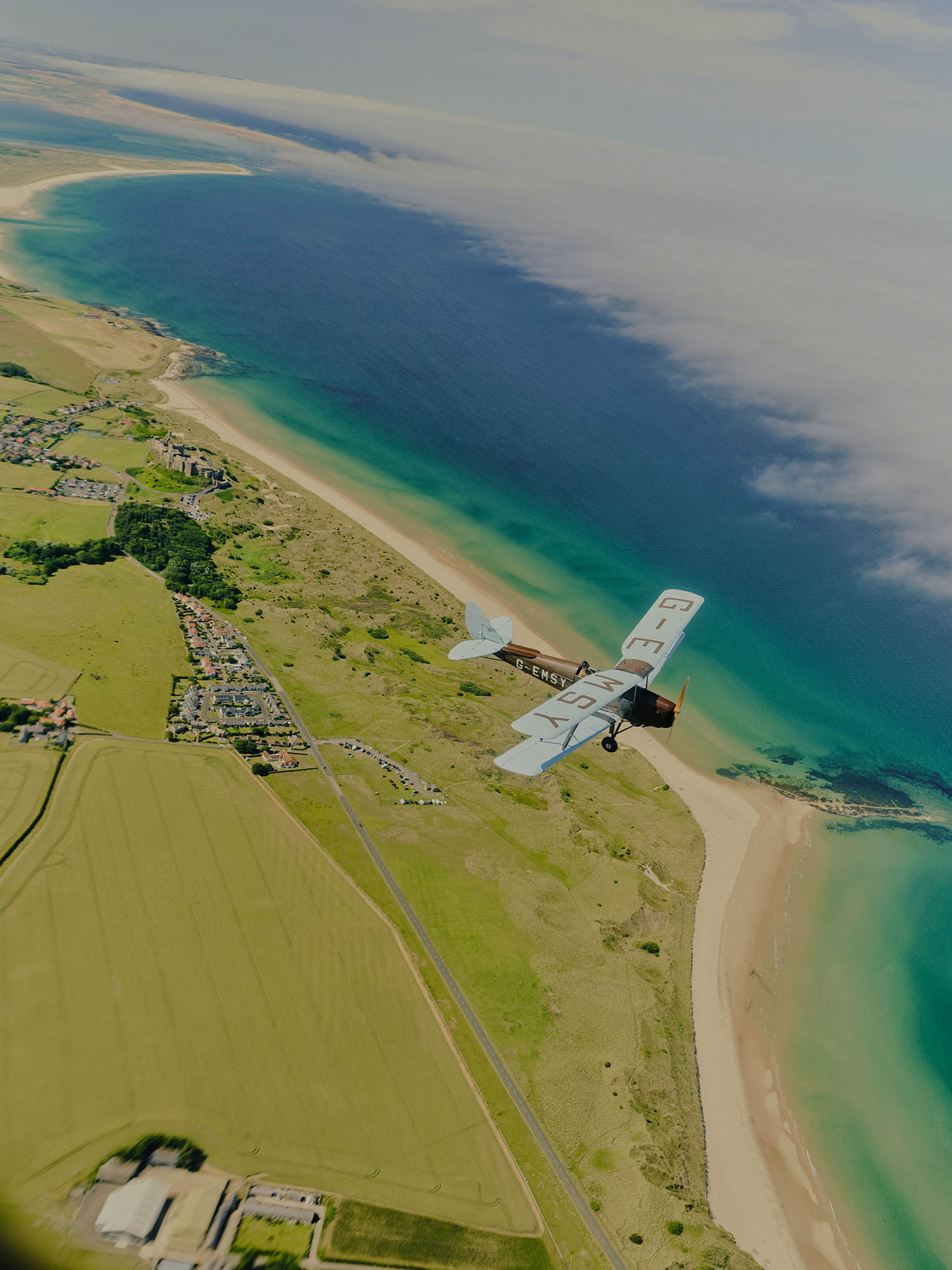 Wings of desire: the Tiger Moth biplane, photographed from the cockpit of a Chipmunk training aircraft, flies above a fogbank along the Northumberland coast